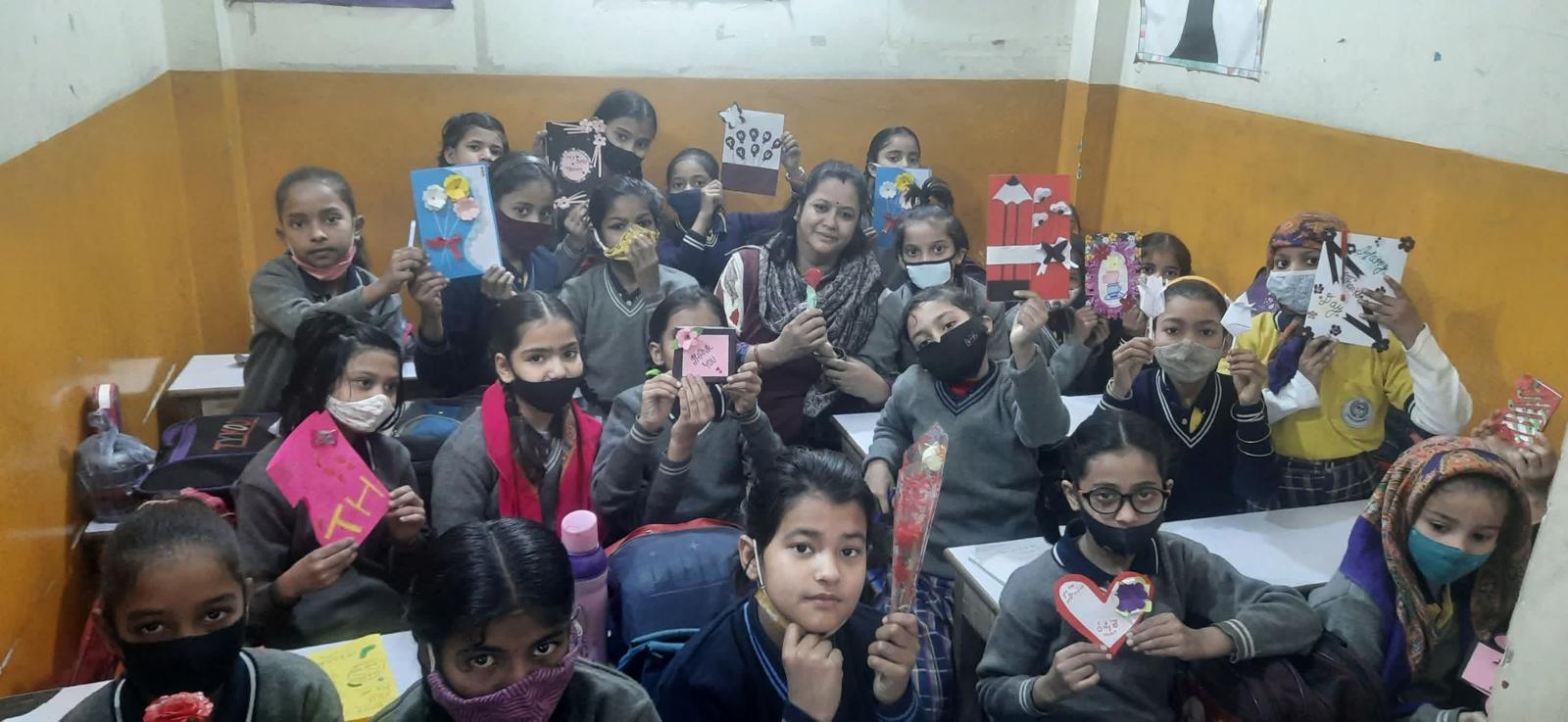 Girls holding menstrual health kits in classroom